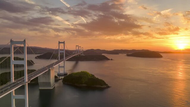 Hyperlapse: Sun sets next to long suspension bridge between small islands
