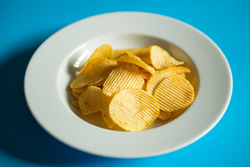 Potato chips served in dish on blue background