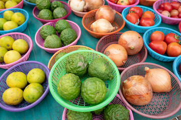Bergamots, limes, onions and tomatoes in baskets on market stall