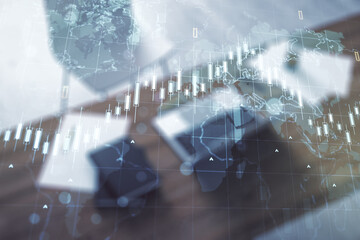 Double exposure of abstract creative financial chart with world map and modern desktop with laptop on background, research and strategy concept