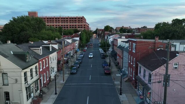 Urban city residential district in evening. Cars on street with headlights on. Rising aerial.
