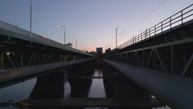 Flight through the middle of the Gdansk Bridge with a view of the modern panorama of Warsaw during sunset.
