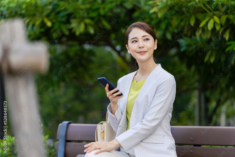 Poster 公園のベンチに座ってスマホを使う女性