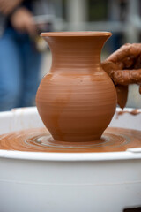 Fototapeta na wymiar A potter makes a pot on a circle. The hands of the master create from clay. Man making ceramic pot.