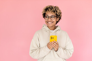 Happy African American woman with phone. Female model in glasses with curly hair holding mobile phone in studio. Portrait, studio shot, emotion concept