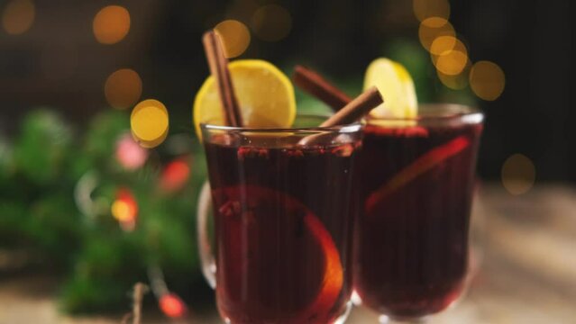 Cinnamon sticks and lemon slices in mulled wine on sparkling garland background
