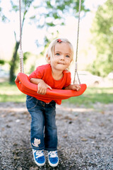 Little girl lay on her stomach on a swing in the park. High quality photo