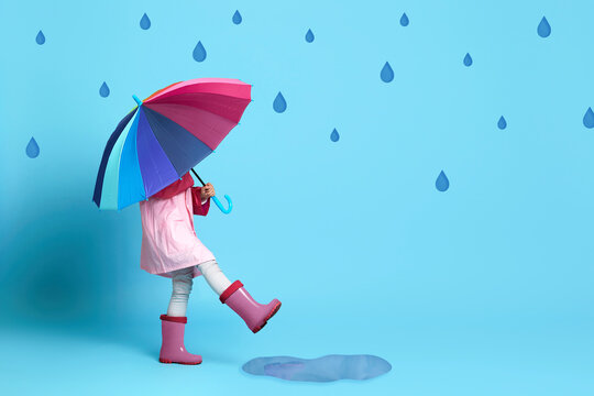 child girl with multicolored umbrella in pink rain coat
