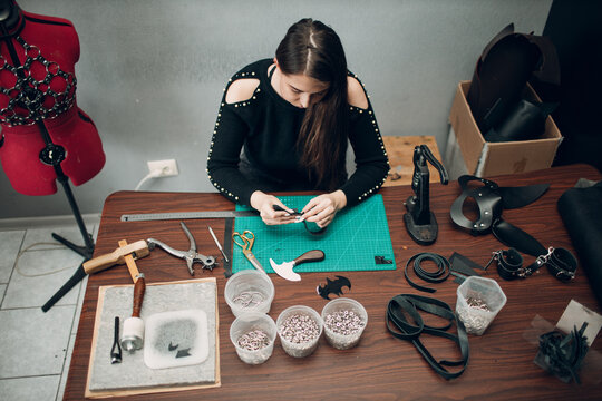 Tanner woman making leather harness belt goods on workshop. Working process of leather craftsman.
