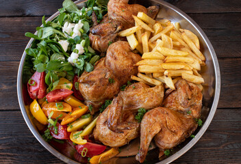 Oven baked chicken with salad and homemade french fries on a large platter