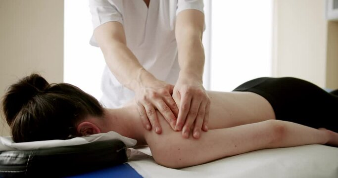 filming of hands massaging back, rehabilitation massage in a professional massage parlor, professional masseur massaging the patient's back and shoulders.