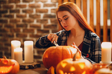Young woman making Halloween pumpkin Jack-o-lantern. Female hands cutting pumpkins with knife