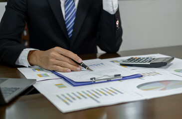 Young Asian businessman financial market analyst sits at their desks and calculate financial graphs showing the results of their investments planning the process of successful business growth