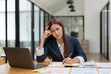 Young asian Woman Office Worker Uses Laptop, Feels Sudden Burst of Pain, Headache, Migraine. Overworked Accountant Feeling Project Pressure, Stress, Massages Her Head, Temples.