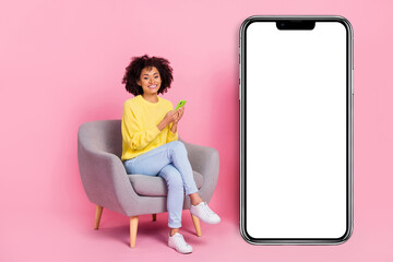 Full length photo of young girl sit armchair use mobile share like download app isolated over pink color background