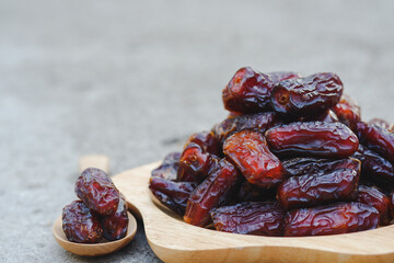 Dates in wooden cups and wooden spoons on cement floor. Muslims like to eat during fasting. (Ramadan) because it can help the body that is exhausted from fasting.