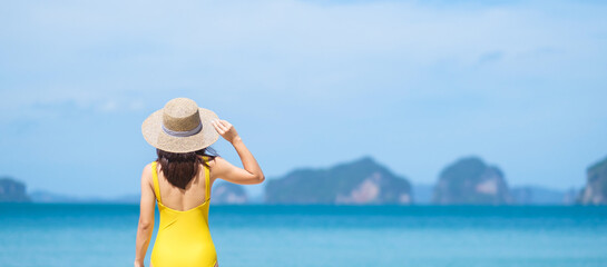 Fototapeta na wymiar Woman tourist in yellow swimsuit and hat, happy traveler sunbathing at Paradise beach on Islands. destination, wanderlust, Asia Travel, tropical summer, vacation and holiday concept