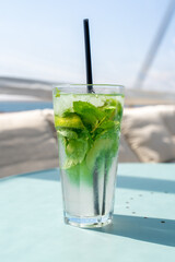 Mojito cocktail in a glass with mint, lime and ice on a blue table. Refreshing drink. selective focus