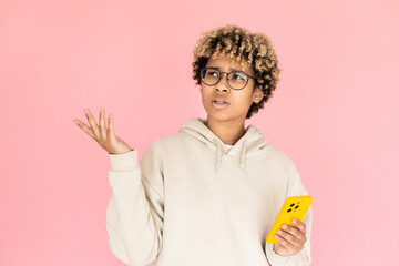 Portrait of bewildered African American woman with phone. Female model in glasses with curly hair looking up. Portrait, studio shot, emotion concept