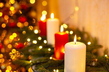 Close up shot of burning candles with blurred Christmas light and fir tree branches background....