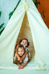 white and black, african-american girls play in a tent, wigwam. kids laugh, have fun. happy childhood © Svetlana