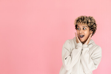 Thrilled African American woman. Female model in hoodie and looking at copy space. Portrait, studio shot, emotion concept