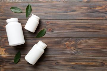 supplement pills with medicine bottle health care and medical top view. Vitamin tablets. Top view mockup bottle for pills and vitamins with green leaves, natural organic bio supplement, copy space