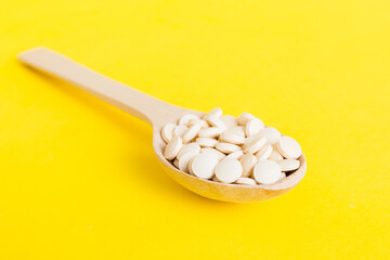 Heap of white pills on colored background. Tablets scattered on a table. Pile of red soft gelatin capsule. Vitamins and dietary supplements concept