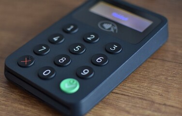 Obraz premium contactless terminal for plastic cards on a wooden brown table
