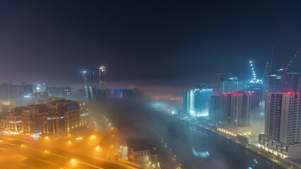 Buildings are covered in thick layer of fog in Business Bay night timelapse.
