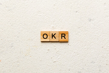 OKR word written on wood block. abbreviation of Objective Key Results text on cement table for your...