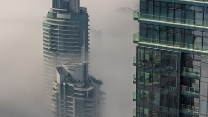 Rare early morning winter fog above the Dubai Marina skyline and skyscrapers rooftops aerial timelapse.
