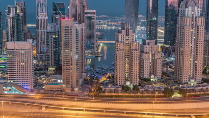 Fototapeta na wymiar Skyscrapers of Dubai Marina near intersection on Sheikh Zayed Road with highest residential buildings night to day timelapse