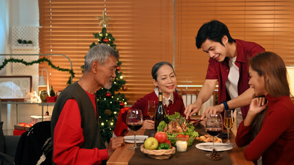 Young coupler celebrating Christmas or New Year with grandparents at cozy home. Holidays and celebration concept