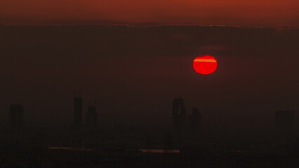 Sunrise over greens and al barsha heights district area night to day timelapse from Dubai marina.