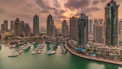 Sunrise over Dubai Marina luxury tourist district with skyscrapers and towers around canal aerial timelapse