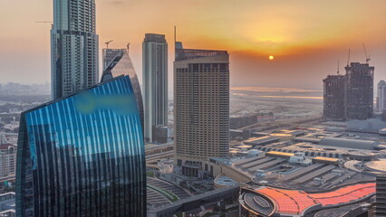 Aerial sunrise panorama of Downtown Dubai with shopping mall and traffic on a street timelapse from above, UAE