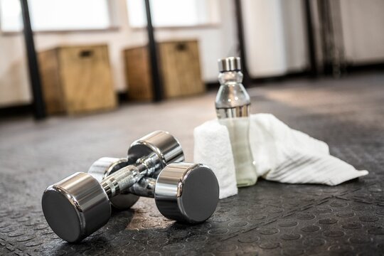 Dumbbells with bottle and napkin on floor 
