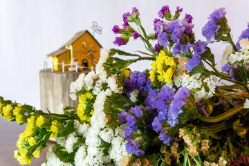 Colorful bouquet of dried flowers on the wooden table with the decorative item on the background . Front view. Copy space. White background