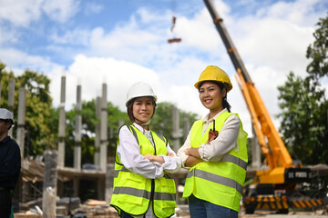 Female architects standing with arms crossed at construction site. Industry, Engineer, construction concept
