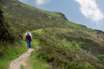 Naklejka na ściany i meble Lynmouth Devon united kingdom, 06, June 2016 Back view of a lady hiker with backpack standing on top of devonshire cliffs walking along devon coast path, Travel concept, vacation.