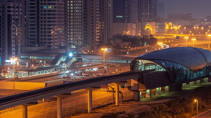 Futuristic building of Dubai metro station and luxury skyscrapers behind in Dubai Marina aerial night to day timelapse