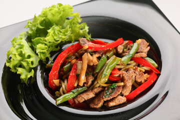 Salad with grilled pork, green beans and paprika on a white plate. Tasty starter for a dinner.