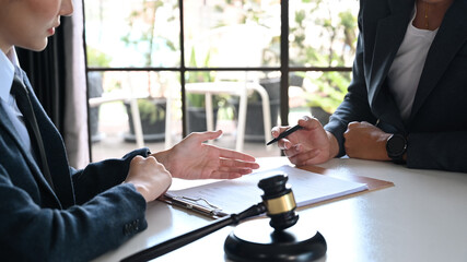 Female lawyer explaining terms, condition on legal document to client before signing on contract at...