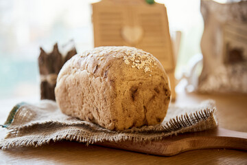 Sourdough organic unleavened bread with oatmeal on rustic sackling. Loaf of natural freshly baked bread. Beige rustic food background.