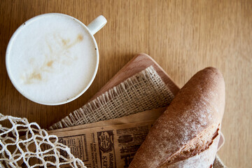 Fresh baguette with cappuccino on wooden table. French breakfast
