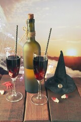 Halloween decorations, in glasses a cocktail of red wine, illumination, against the backdrop of a landscape with a sunset, evening, October