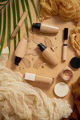 Bottles of three different shades of makeup foundation on beige background with palm leaf