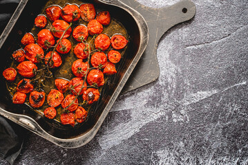 Tray of roasted red cherry tomatoes with garlic, herbs and olive