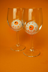 toy eyes in wine glasses on an orange background with a place for text, halloween concept